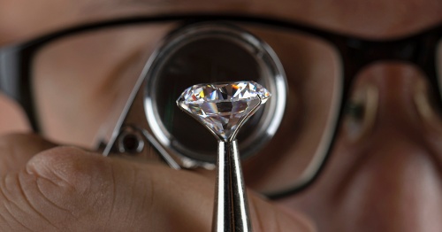 Man looking at diamond through loupe.