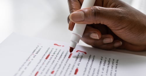 Hand with red pen correcting document